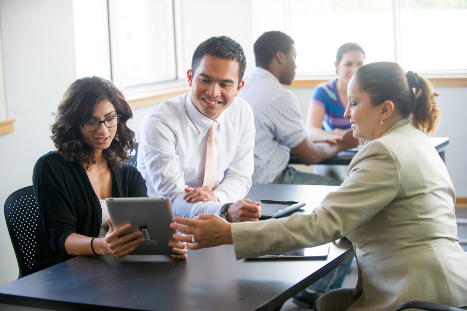 professionally dressed college students working together on a tablet.