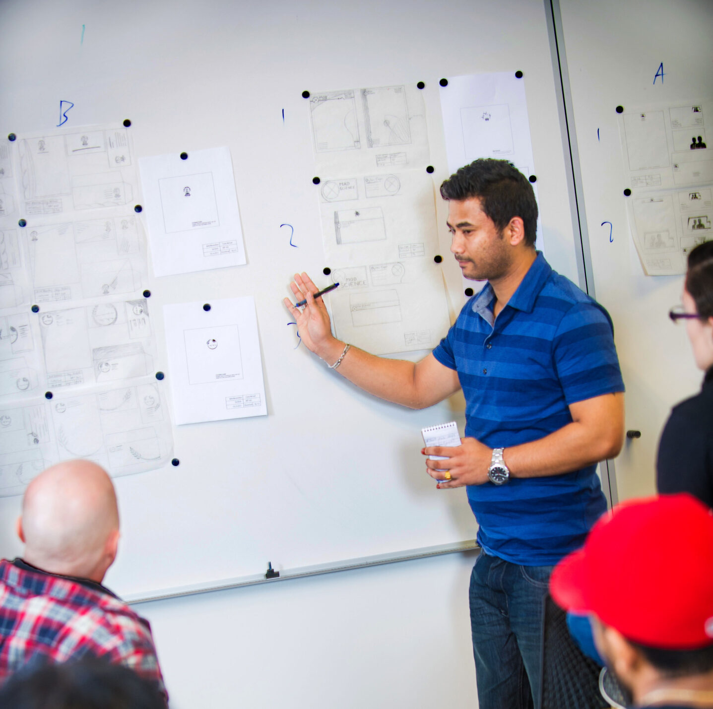 Student presenting design layouts on a whiteboard.