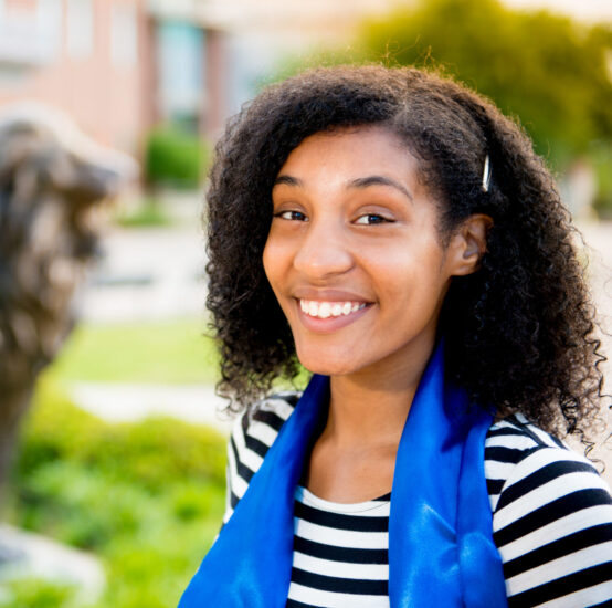 Young woman smiling while standing in front of university lion statue.