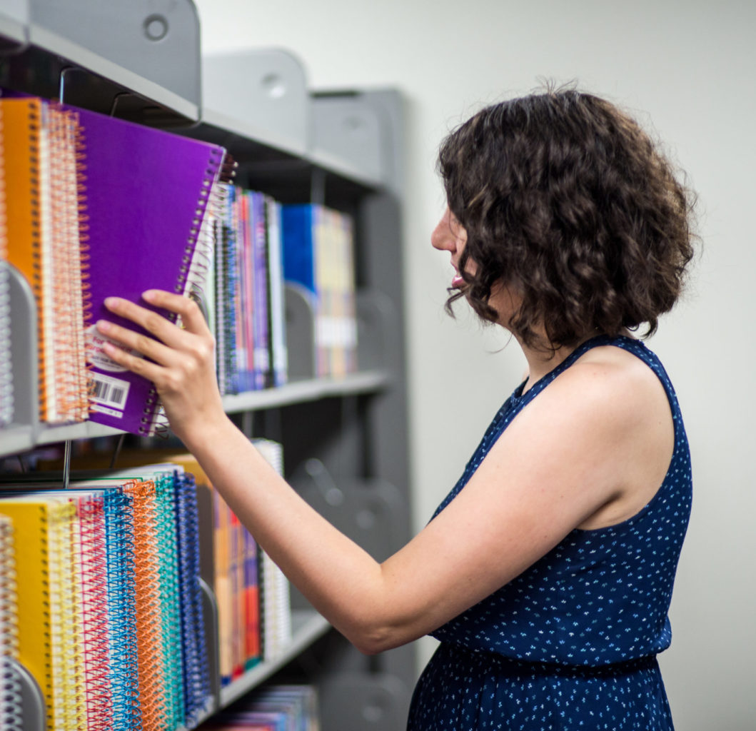 Lady picking out book at the library.