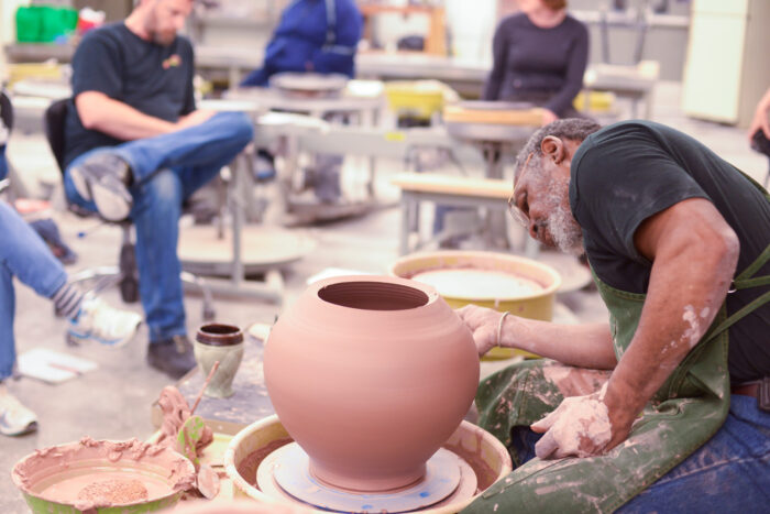 the professor creates a ceramic vase in front of the students.