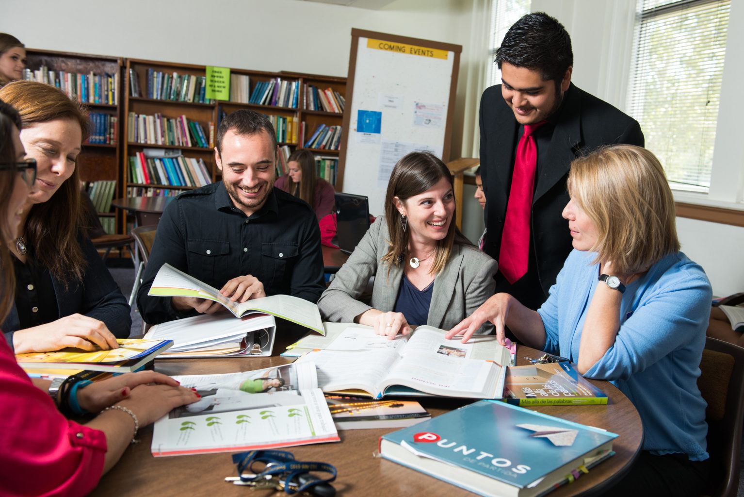 group of graduate students gathered around a table with spanish book labeled Puntos.