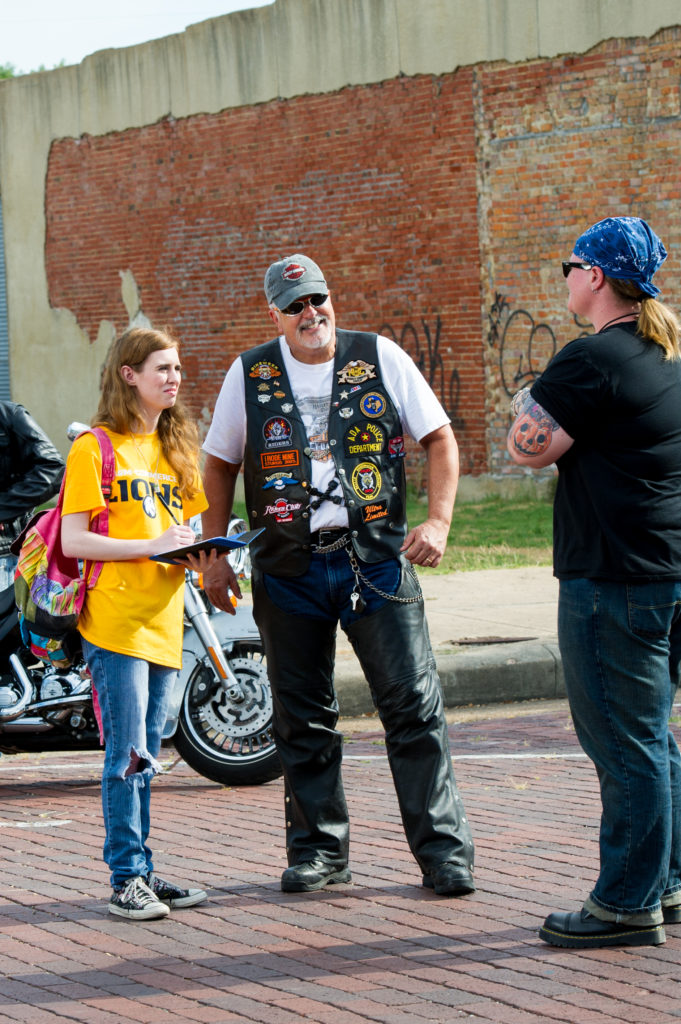 Woman interviewing two bikers.