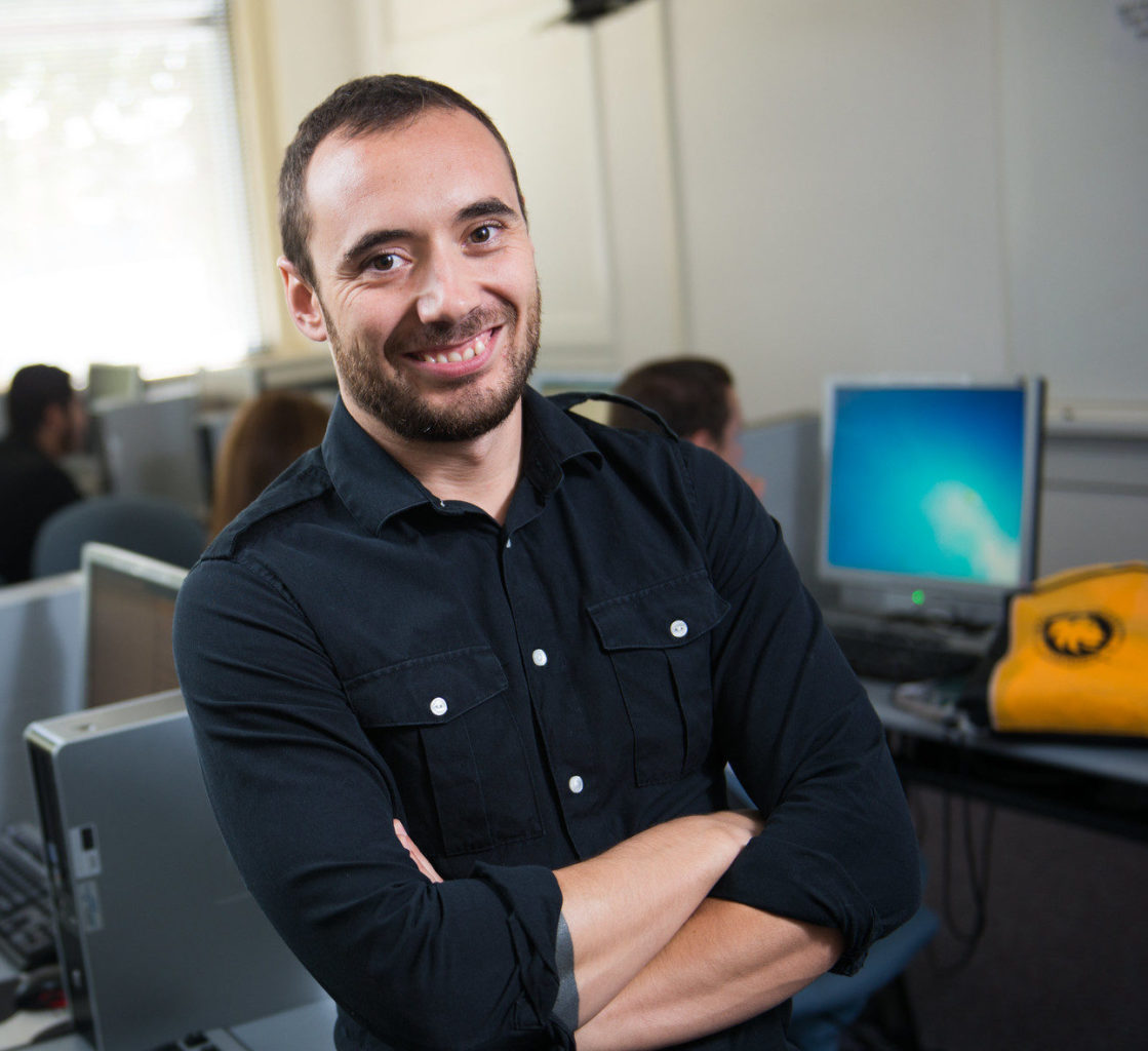 Hispanic man standing in computer lab.