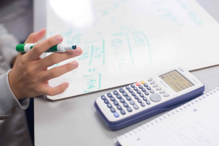 Image of calculator and someone holding a marker.