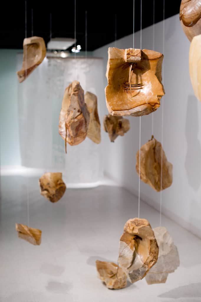 Broken pieces of pottery suspended from clear line.