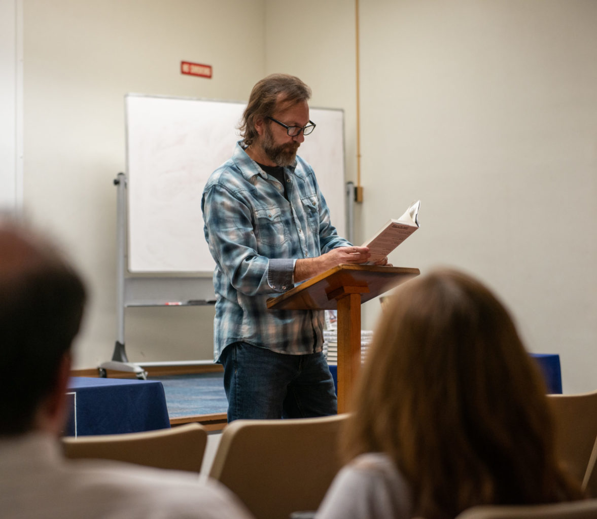 Man reading book to a classroom.