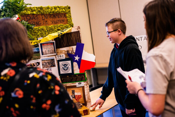 A student present a history project to two teachers.