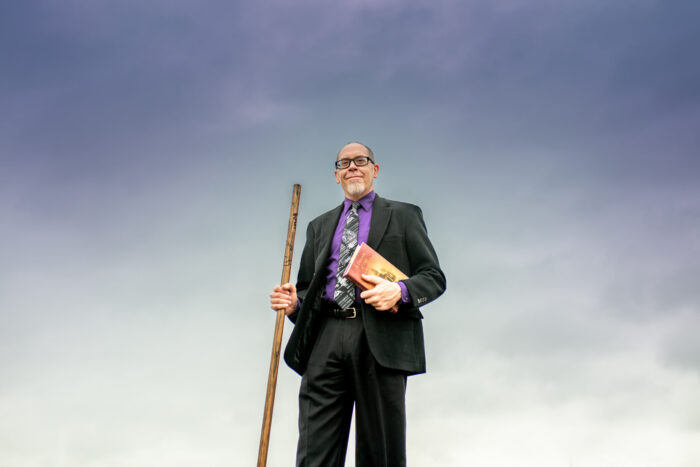 Dr. Smith holding a wood cane and his latest book