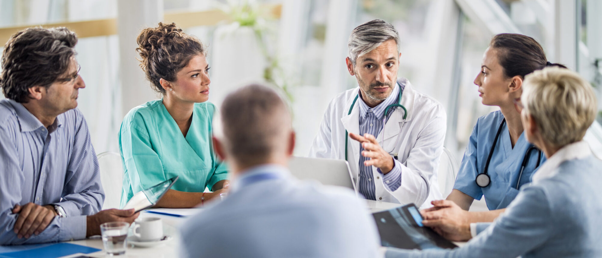 Doctor and his colleagues talking to team of business people on a meeting in the hospital.