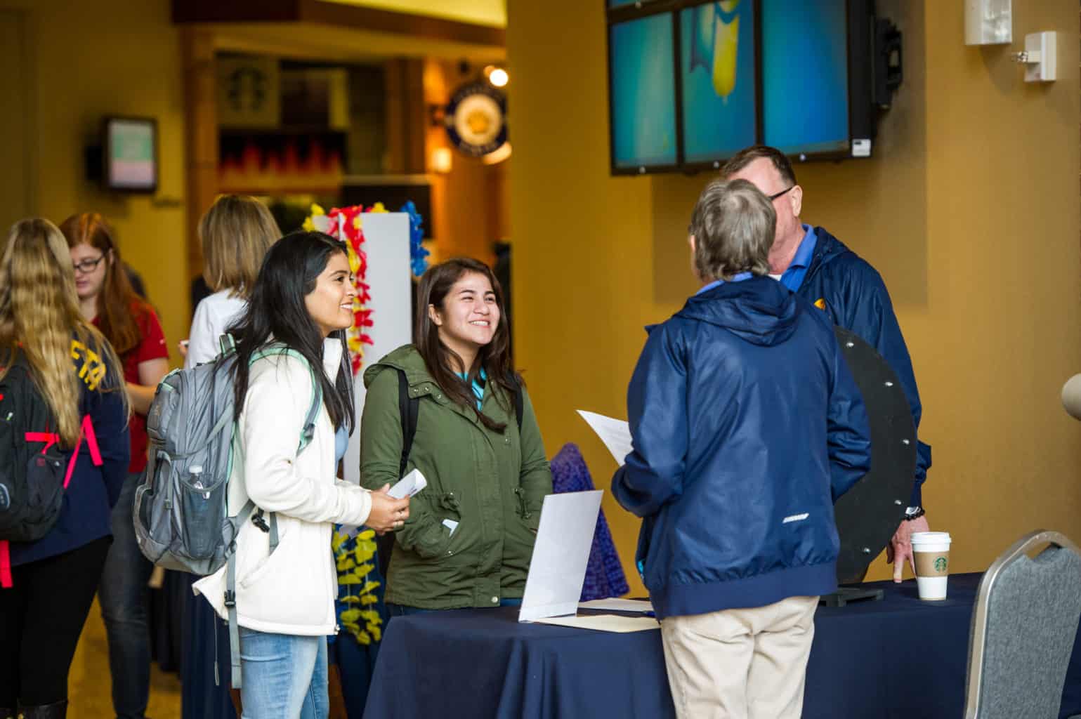 Two students talking with two professors during a student organizations fair on campus.