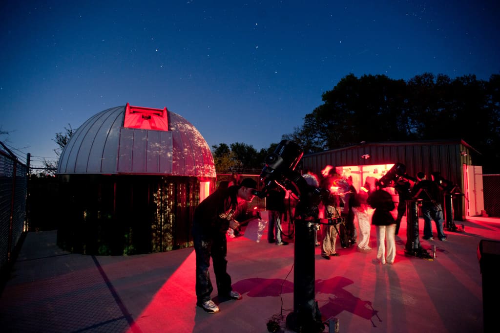 Students viewing stars with giant telescope.