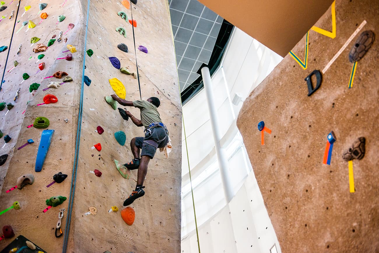 Student climbing rock wall.