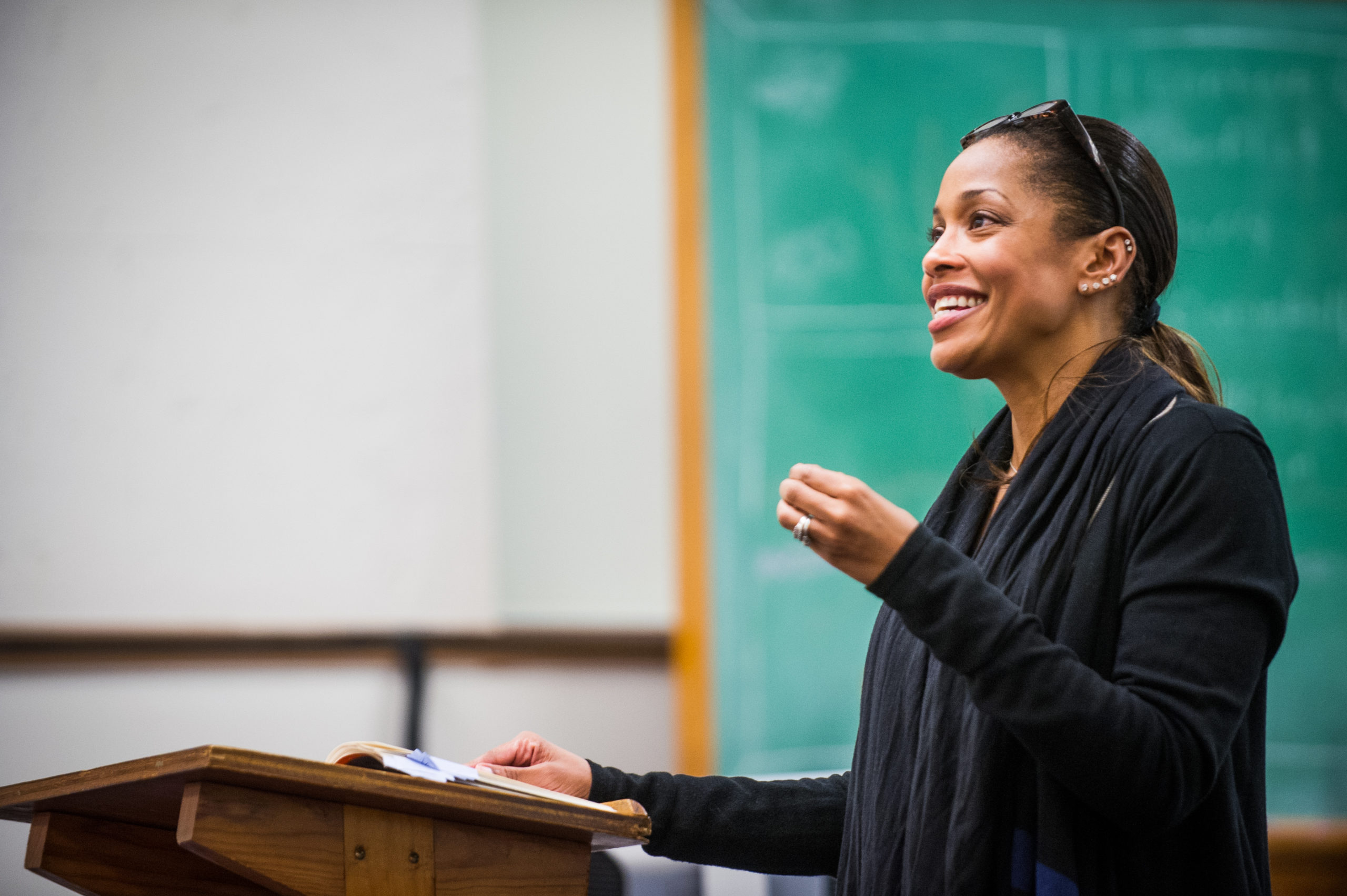 A female educator with big smile reading a poem to audience.