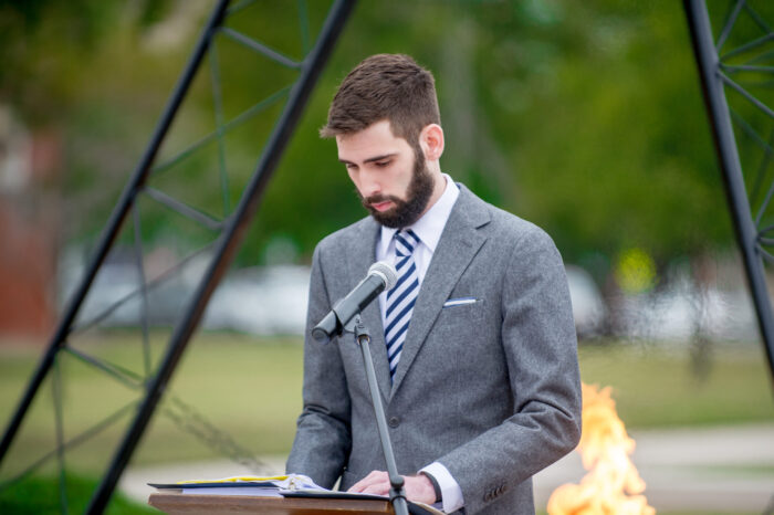 Young man speaking to audience at a veterans vigil.