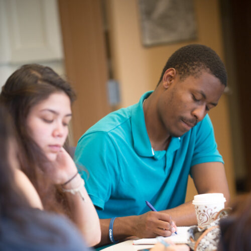 A male and female writing at a table.