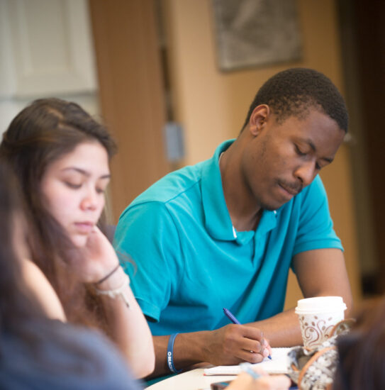 A male and female writing at a table.