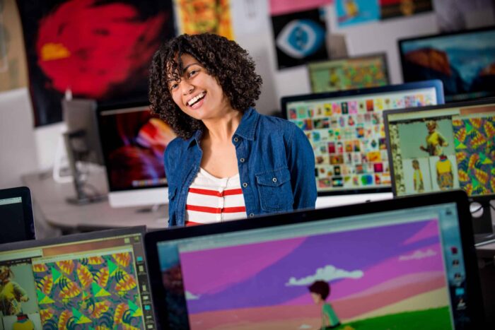 Student smiling around many computers.