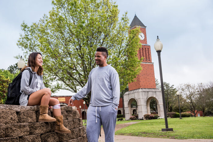 Two students talking in an outside space of the A&M-Commerce campus at Navarro College.