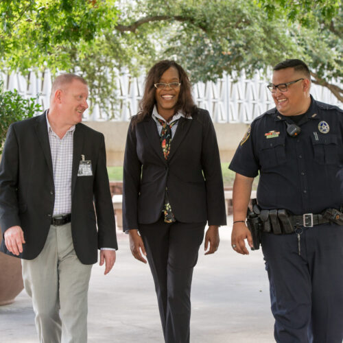 Three professionals walking, smiling, and talking to each other.