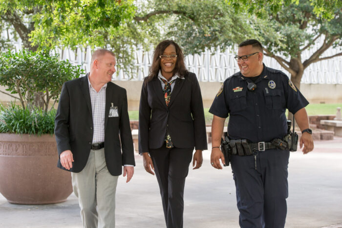 Three professionals walking, smiling, and talking to each other.