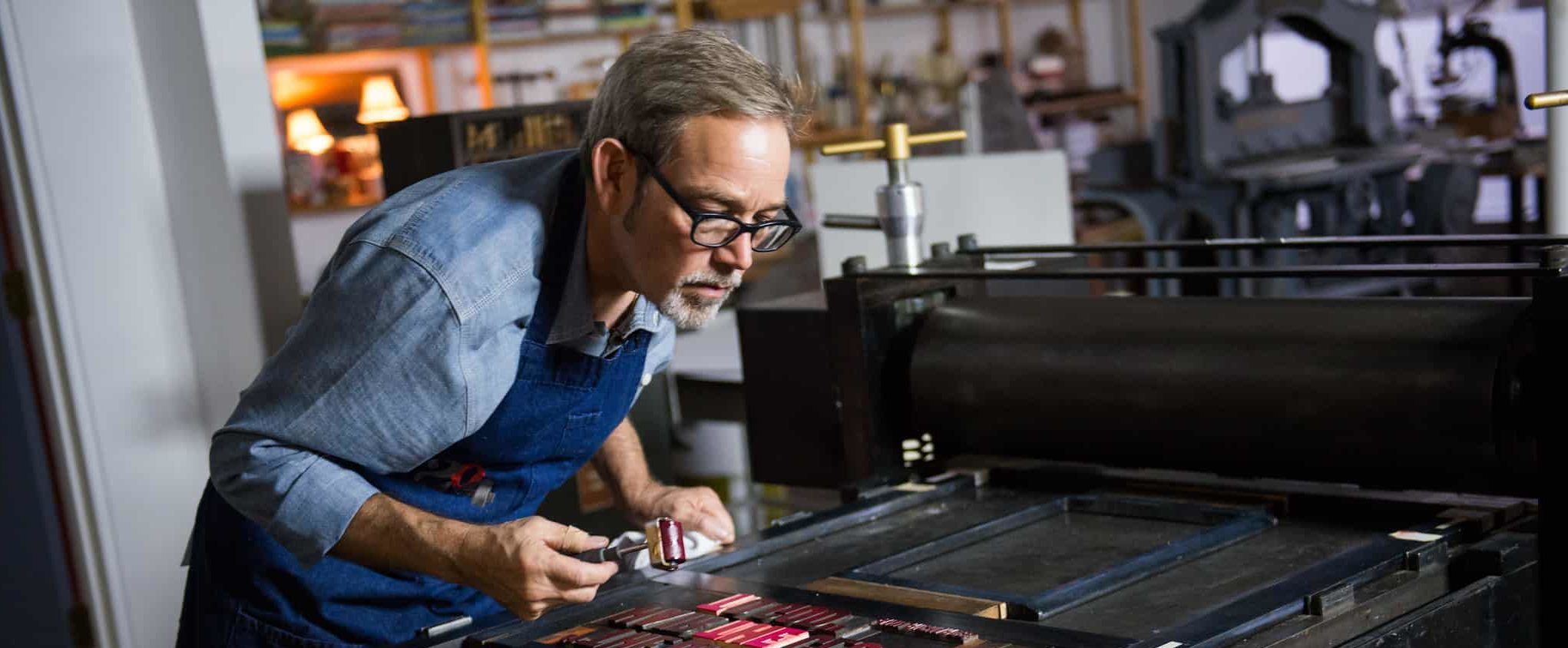 Man working on letter press for art project.