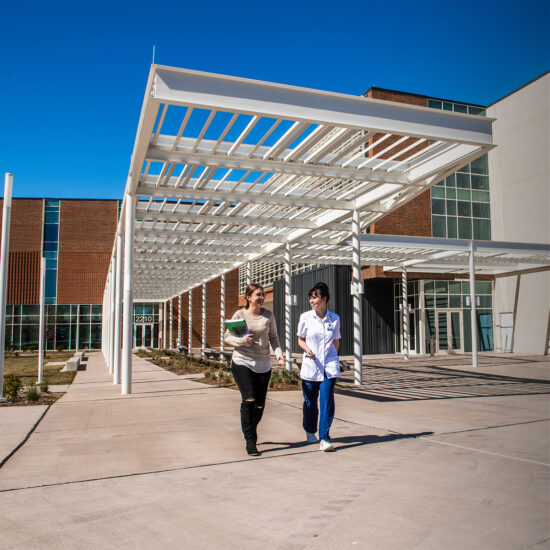 Two female students walking out of the health building