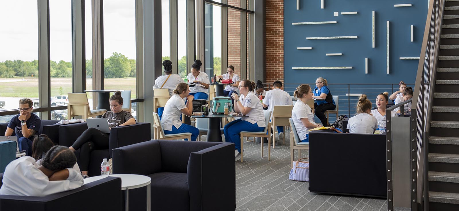 different groups of students eating, reading and talking in a student lounge at the Rellis location.