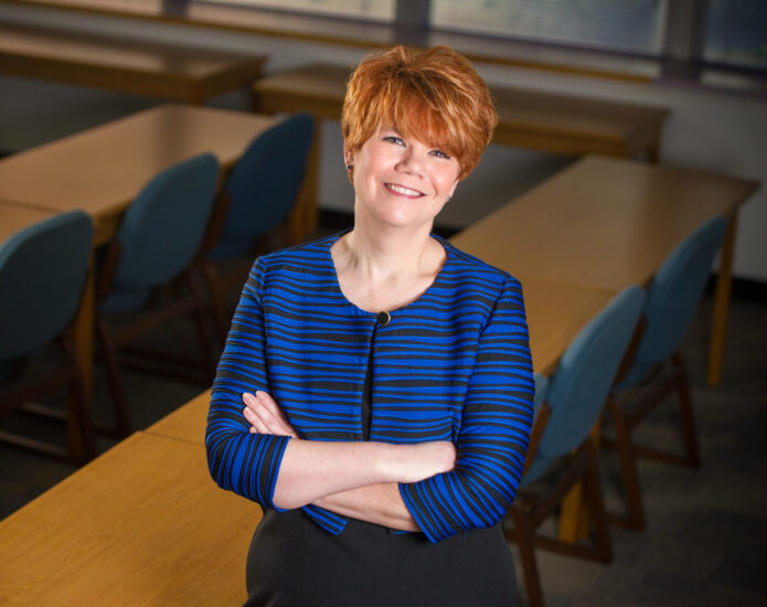 Female educator standing in classroom smiling.