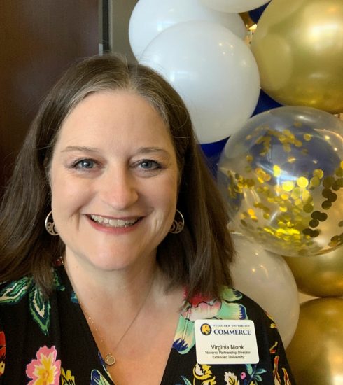 A woman stands in front of gold and white balloons.