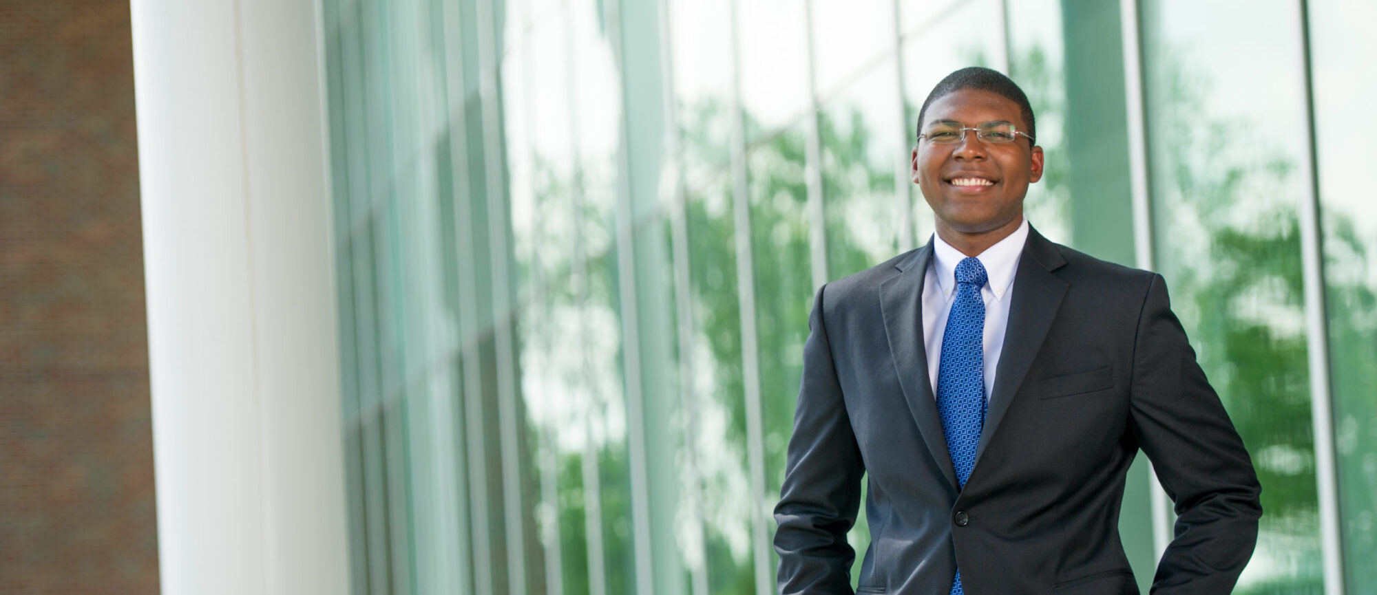 Man wearing professional attire with suit and blue tie.