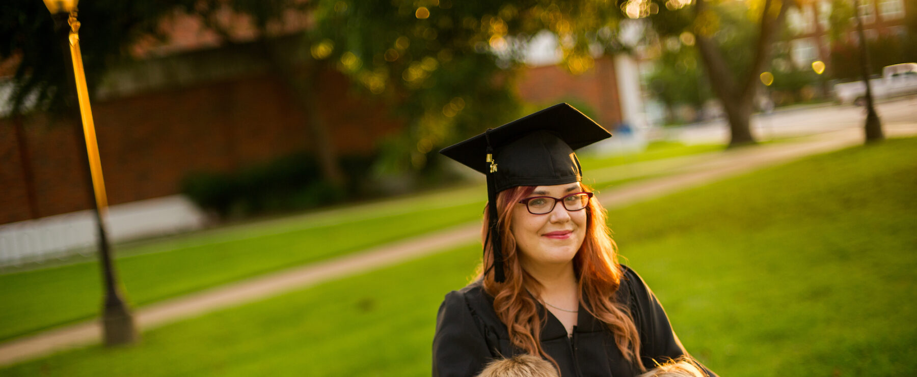 Graduate in cap and gown taking a picture with her kids.