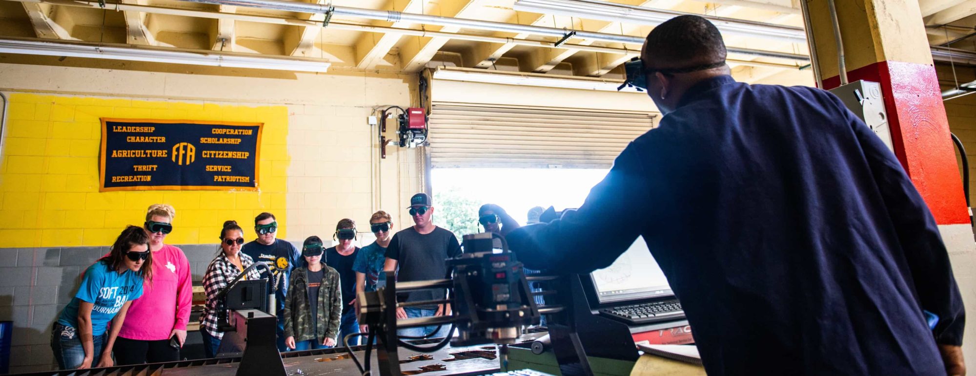 Instructor showing how to use a cutting wood machine to students.