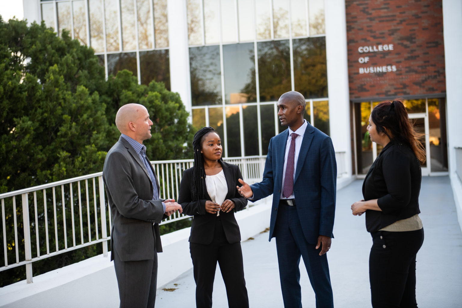 A group of professors and students talking outside of the College of Business building.