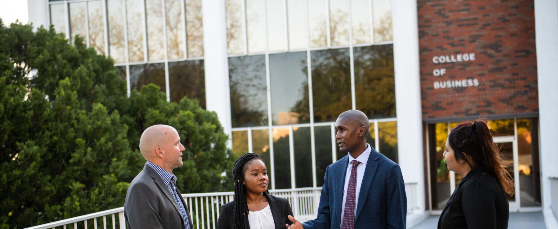 A group of professors and students talking outside of the College of Business building.