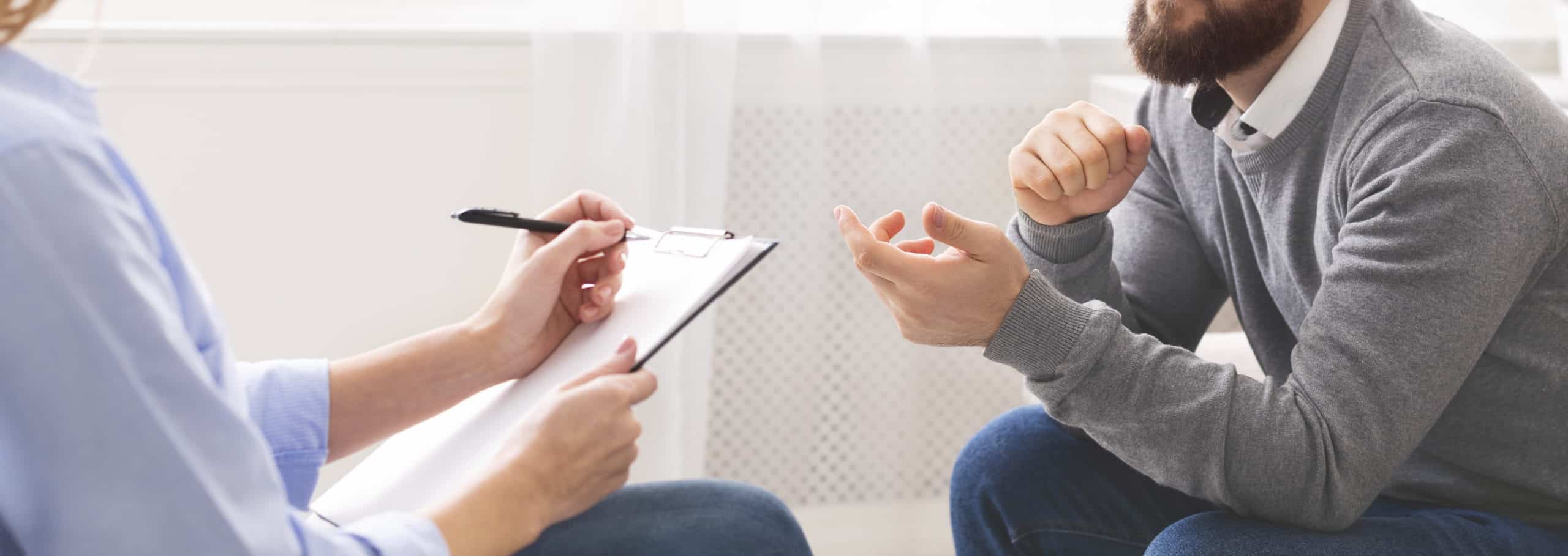 A male speaking with someone using a board talking about problems.