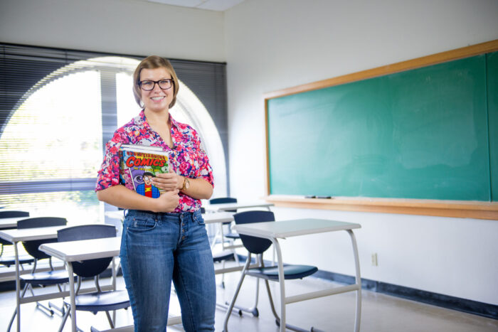 Teacher holding books in a classroom.