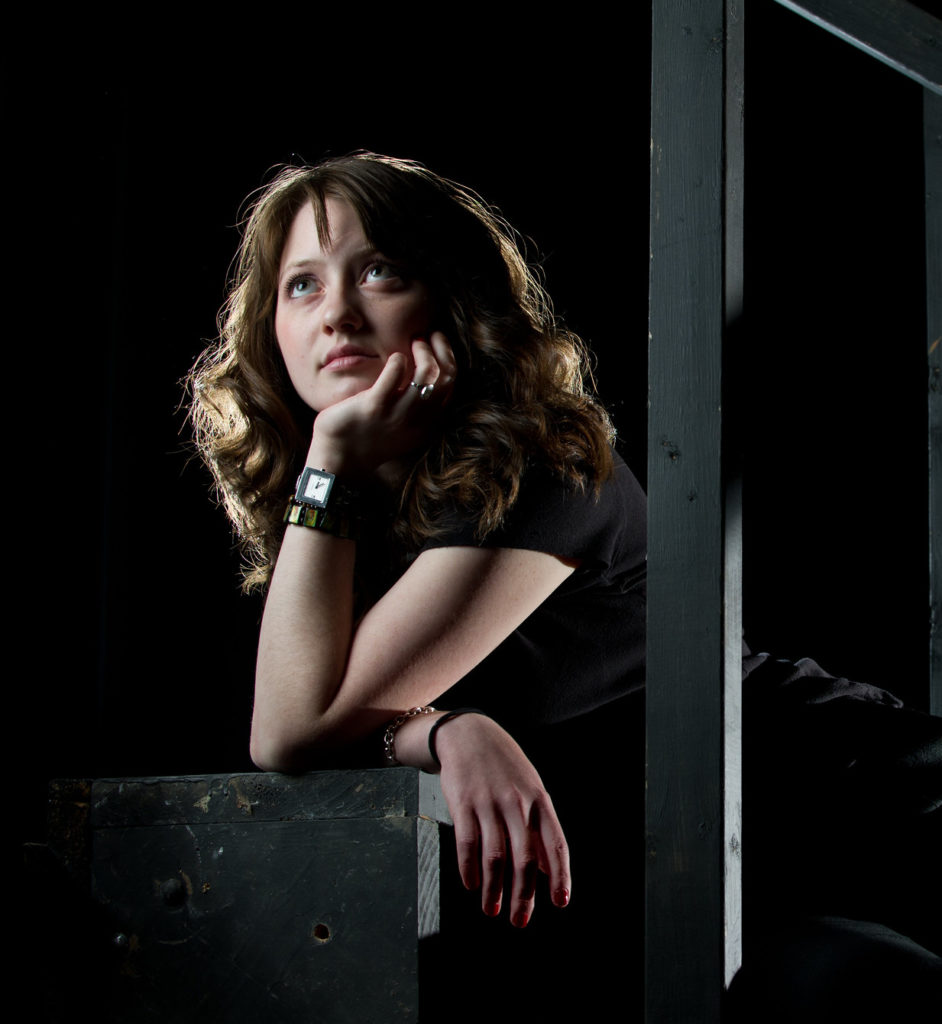 Young actress peering towards stage lights