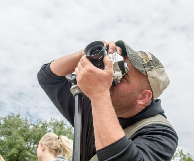 man shooting photos with an older man and woman in the background.