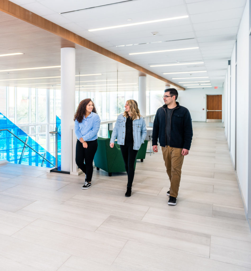 Three students walking and talking inside the new Nursing Health Sciences building on the TAMUC campus.