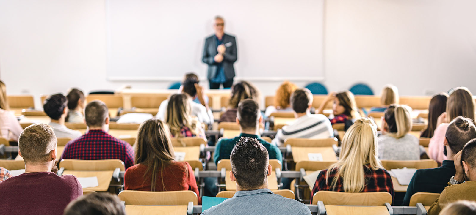 Back view of large group of students paying attention on a class at lecture hall.