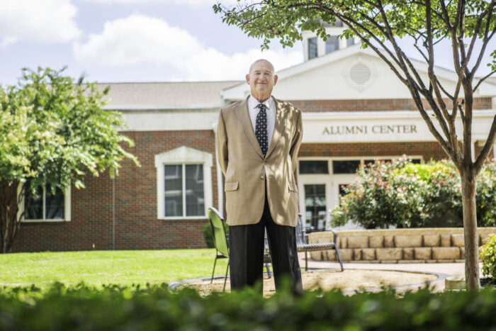 An alumni standing in front of the Alumni Center.