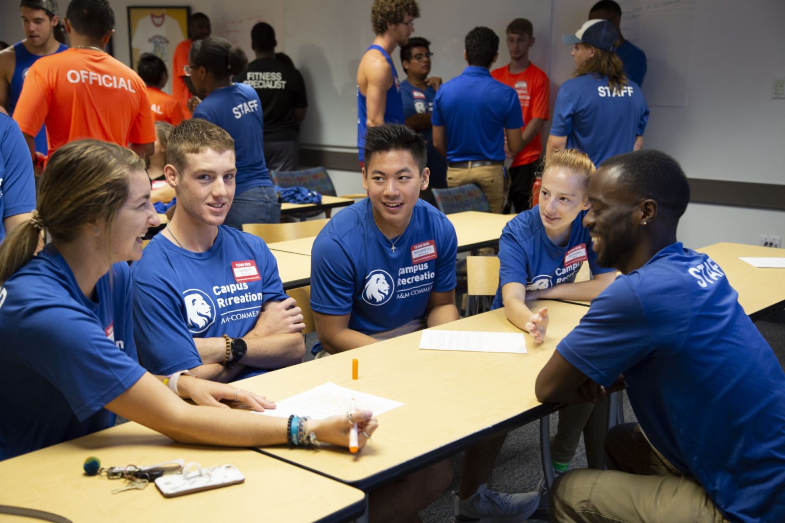 Campus Recreation employees sitting on a table smiling. 