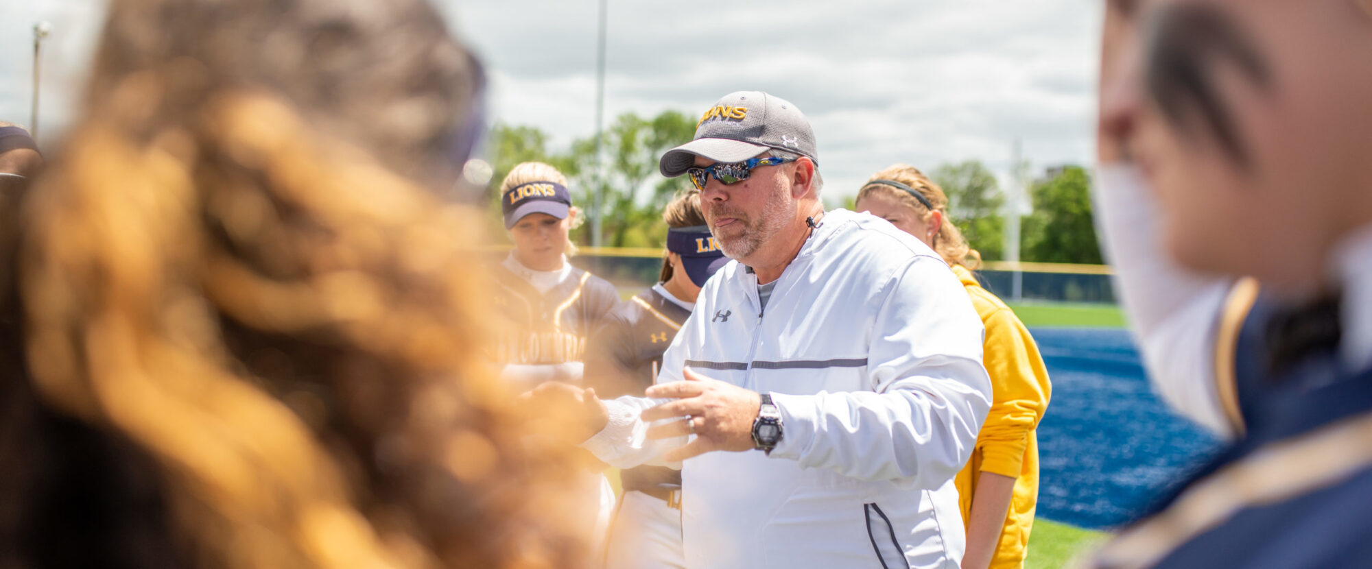 Coach instructing softball team.