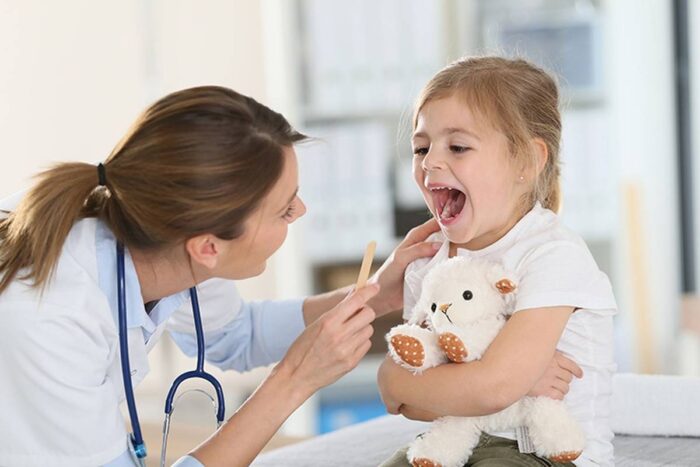 Nurse examining the mouth of a young patient.