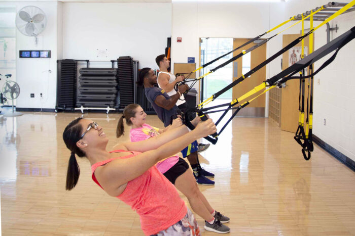 Students exercising using TRX bands during a group fitness class in the Activity Room.
