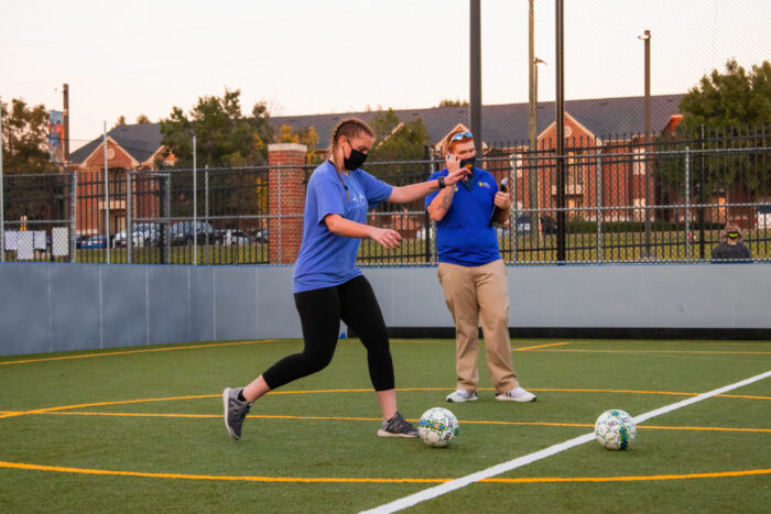 TAMUC student kicking a soccer ball.