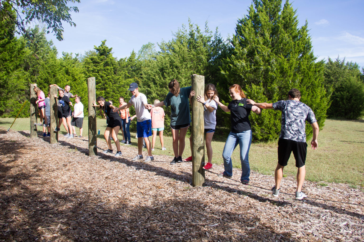 A group of student walking on a line few inches above the ground at the challenge course. 