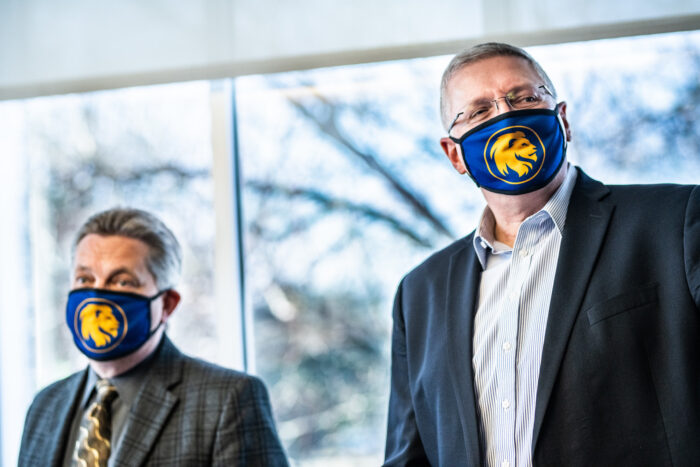 Two faculty members wearing masks at a presentation.