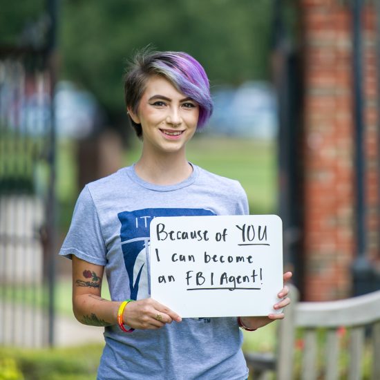 A student with a sign appropriating her opportunity.